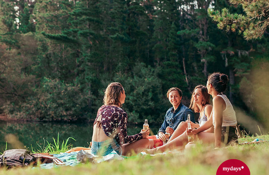 Unternehmungen mit Freunden: vier Freunde genießen den Nachmittag am See bei einem Picknick.