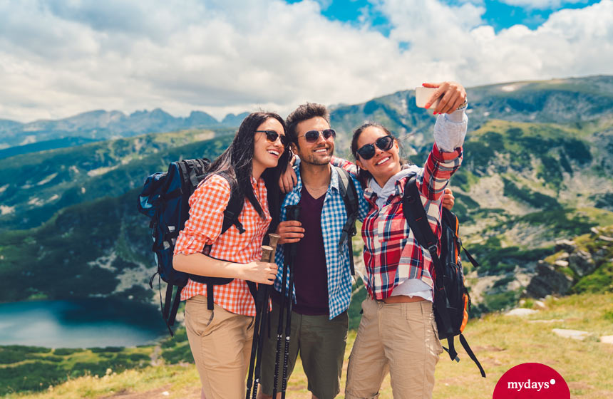 Drei Wanderer schießen ein Selfie auf dem Gipfel - unsere Nummer eins der schönsten Unternehmungen mit Freunden.
