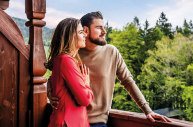 Paar auf Balkon blickt in die Berge
