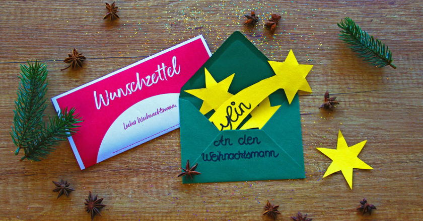 Roter Wunschzettel und Briefumschlag mit Sternen auf Holzboden
